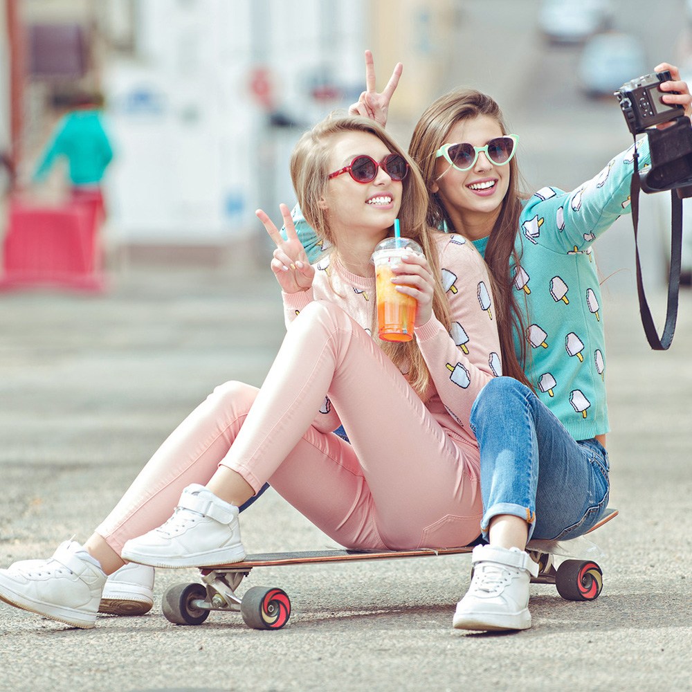 Two young girs take a selfie on a skateboard